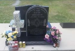 Black granite headstone with a cross and flowers, honoring Caird David Abraham (1955-2016) — Mackay Monumental Masons In Glenella, QLD