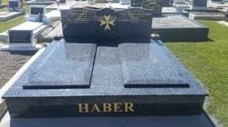 Dark granite tombstone with gold lettering and a Maltese cross in a cemetery — Mackay Monumental Masons In Glenella, QLD