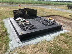 Black granite tombstone with cross and two sunken beds filled with black stones, on a concrete base — Mackay Monumental Masons In Glenella, QLD