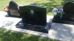 Black headstone in a cemetery with a framed picture and flowers — Mackay Monumental Masons In Glenella, QLD