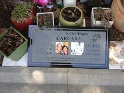 Grave marker for Caruana family, with photos of two adults, surrounded by potted plants — Mackay Monumental Masons In Glenella, QLD
