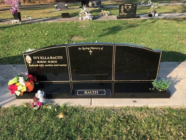 Black granite headstone with flowers in a cemetery.