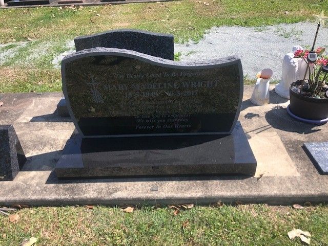 Several black granite headstones at a cemetery, various shapes and sizes, reflecting sky.