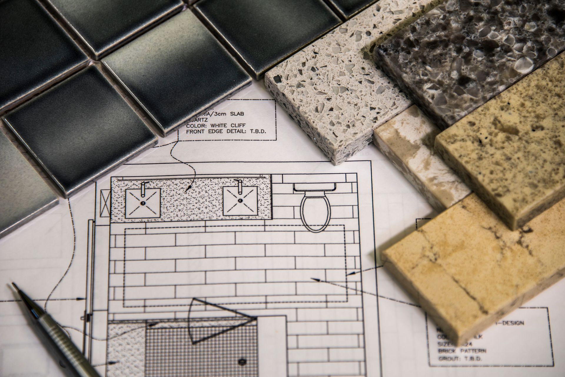Assorted tile samples arranged on top of a bathroom design blueprint.