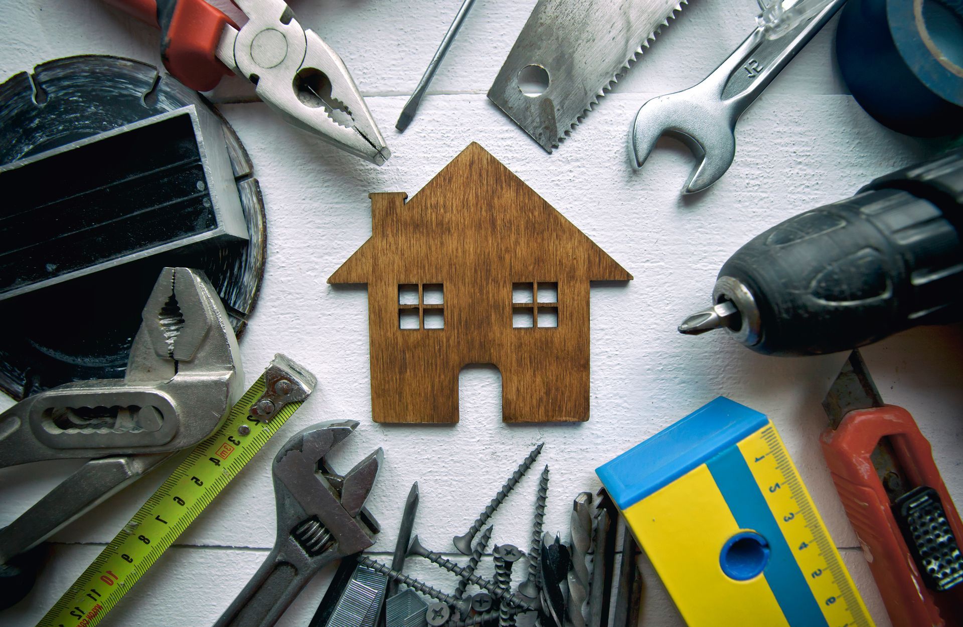 Wooden house surrounded by various tools, suggesting home repair or construction.