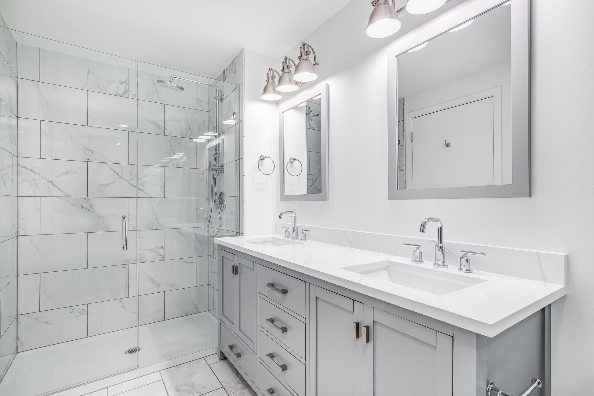 Modern bathroom with glass shower, double vanity, and white marble finishes.