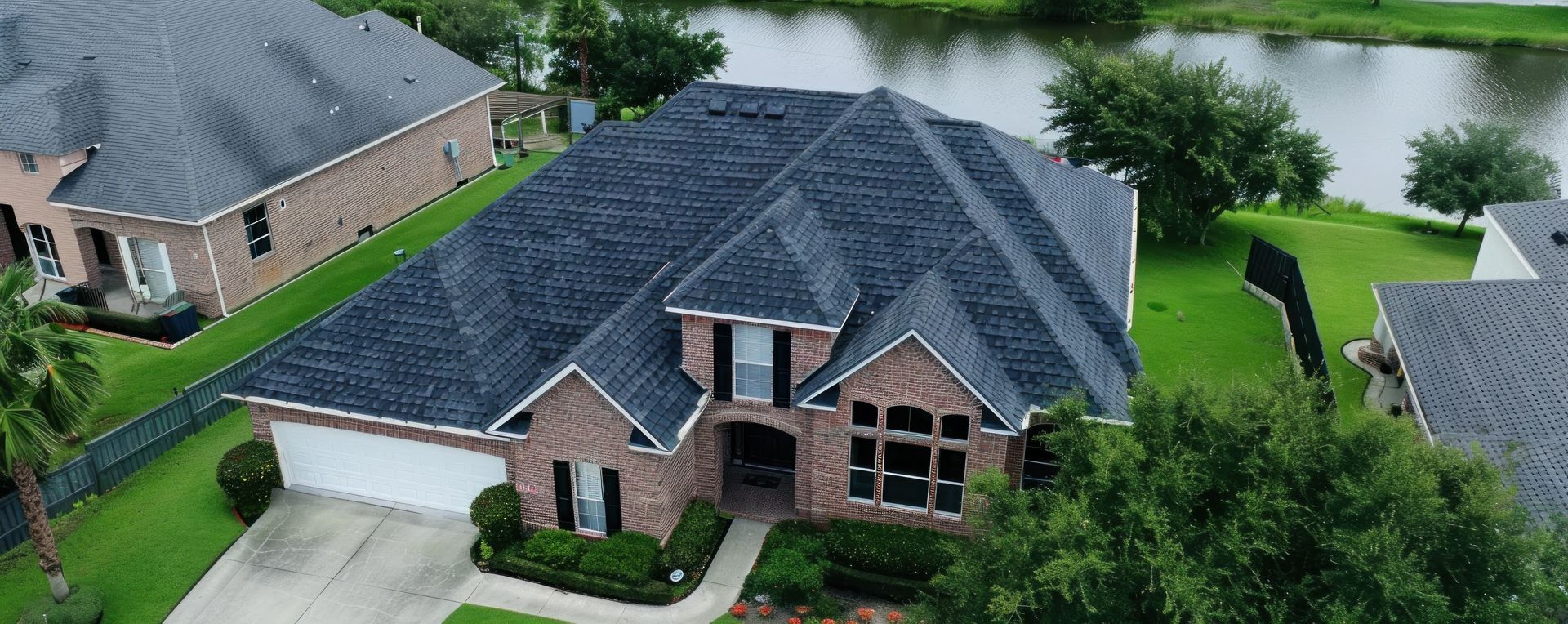 An aerial view of a house with a dark gray metal roof and chimneys.
