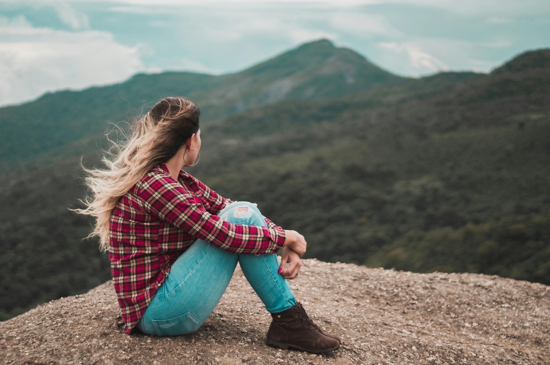 Woman sitting overlooking mountaintop.