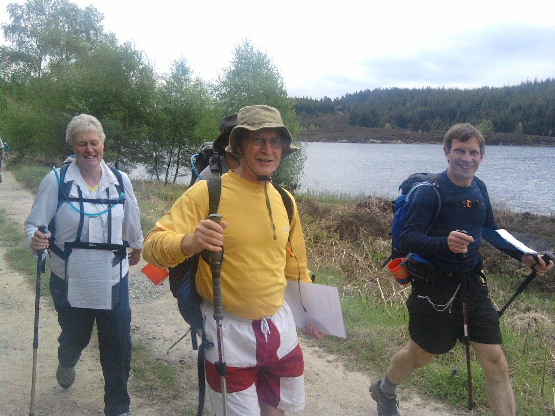 Three men walking next to a lake
