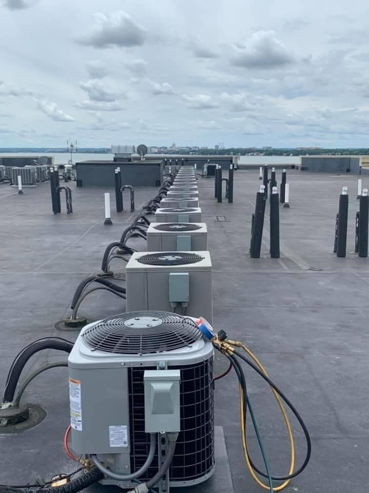 A row of air conditioners are sitting on top of a roof.