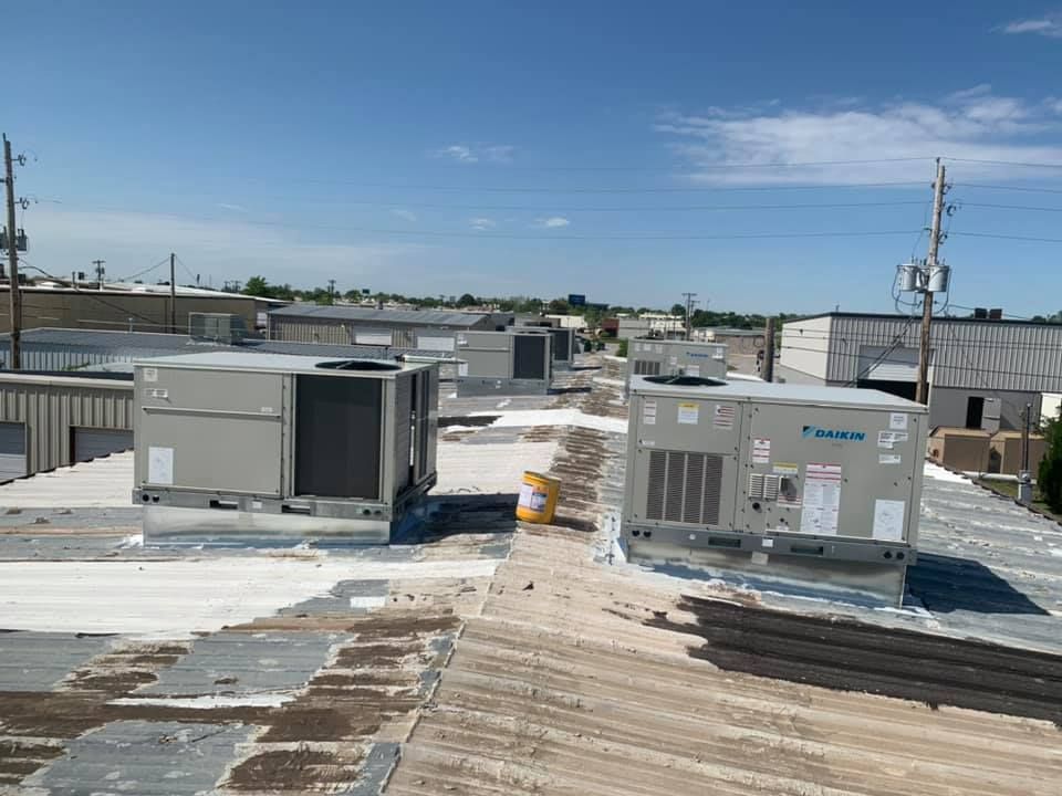 There are a lot of air conditioners on the roof of a building.