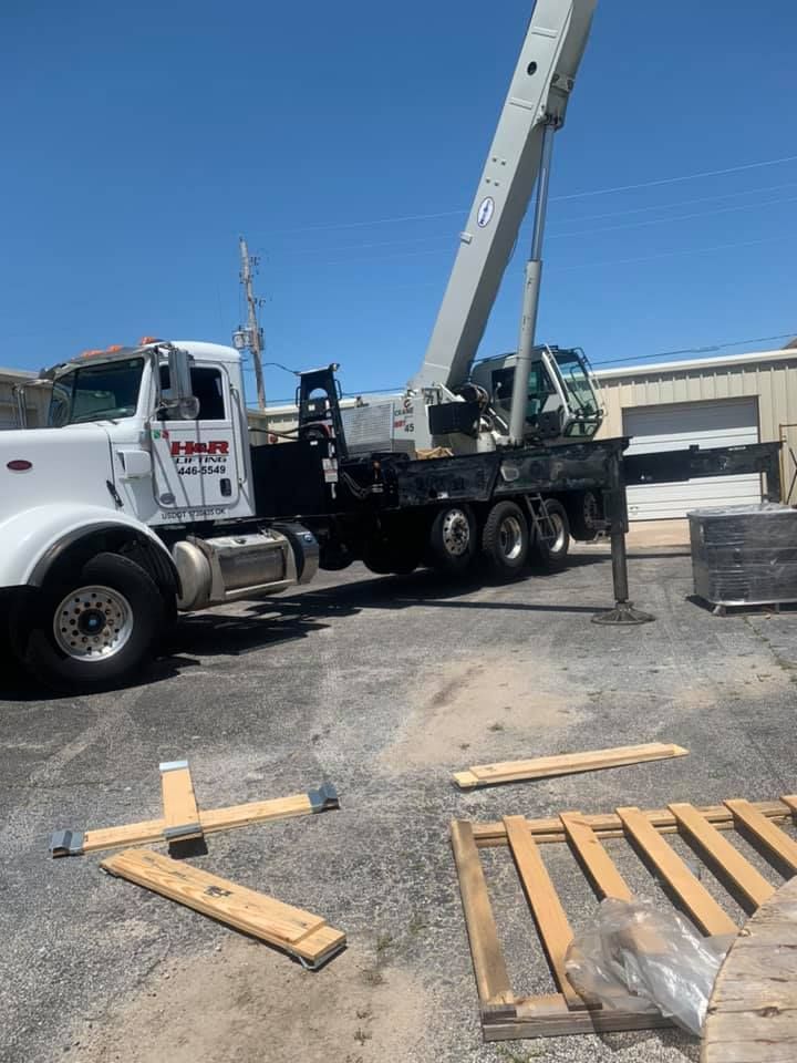 A truck with a crane attached to it is parked in a parking lot.