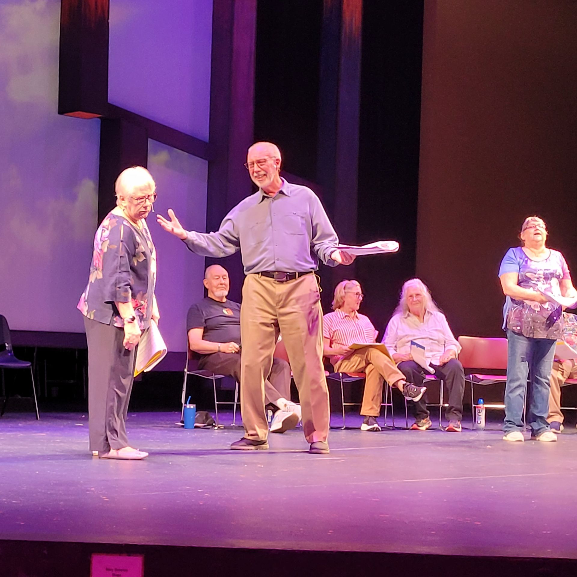 A group of people standing on a stage with purple lights