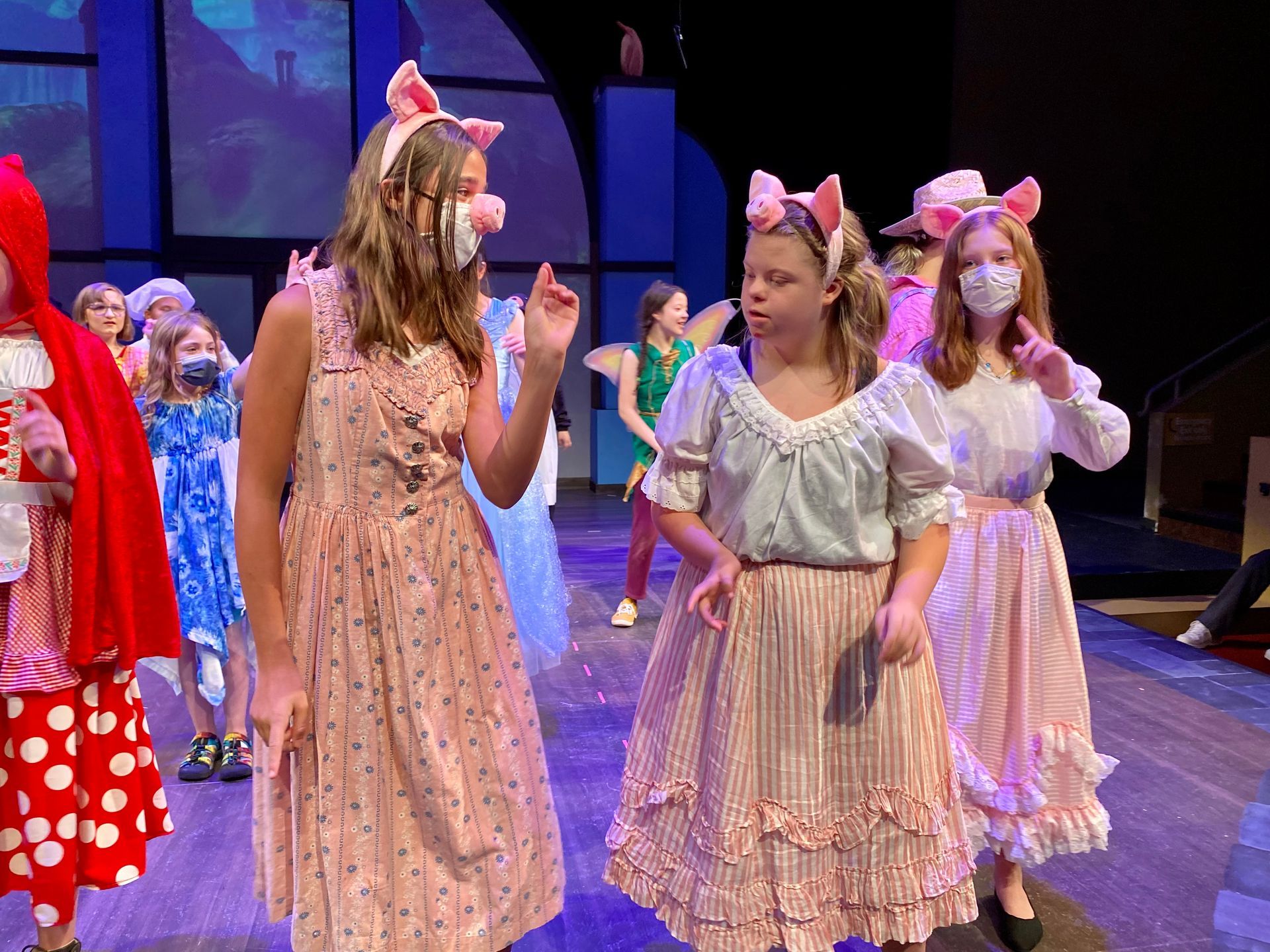 A group of young girls are standing on a stage wearing pig ears.