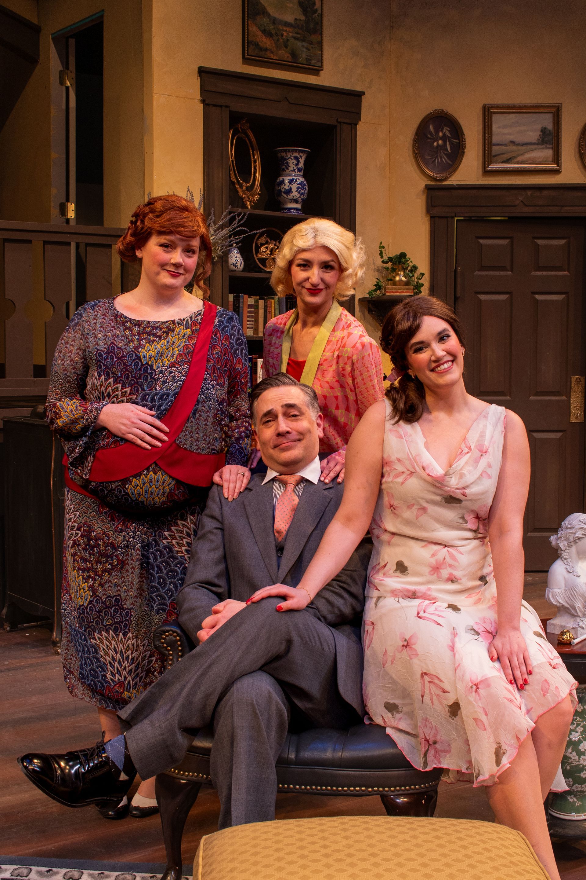 Four people posing, smiling, in vintage clothing, inside a home with dark wood accents.