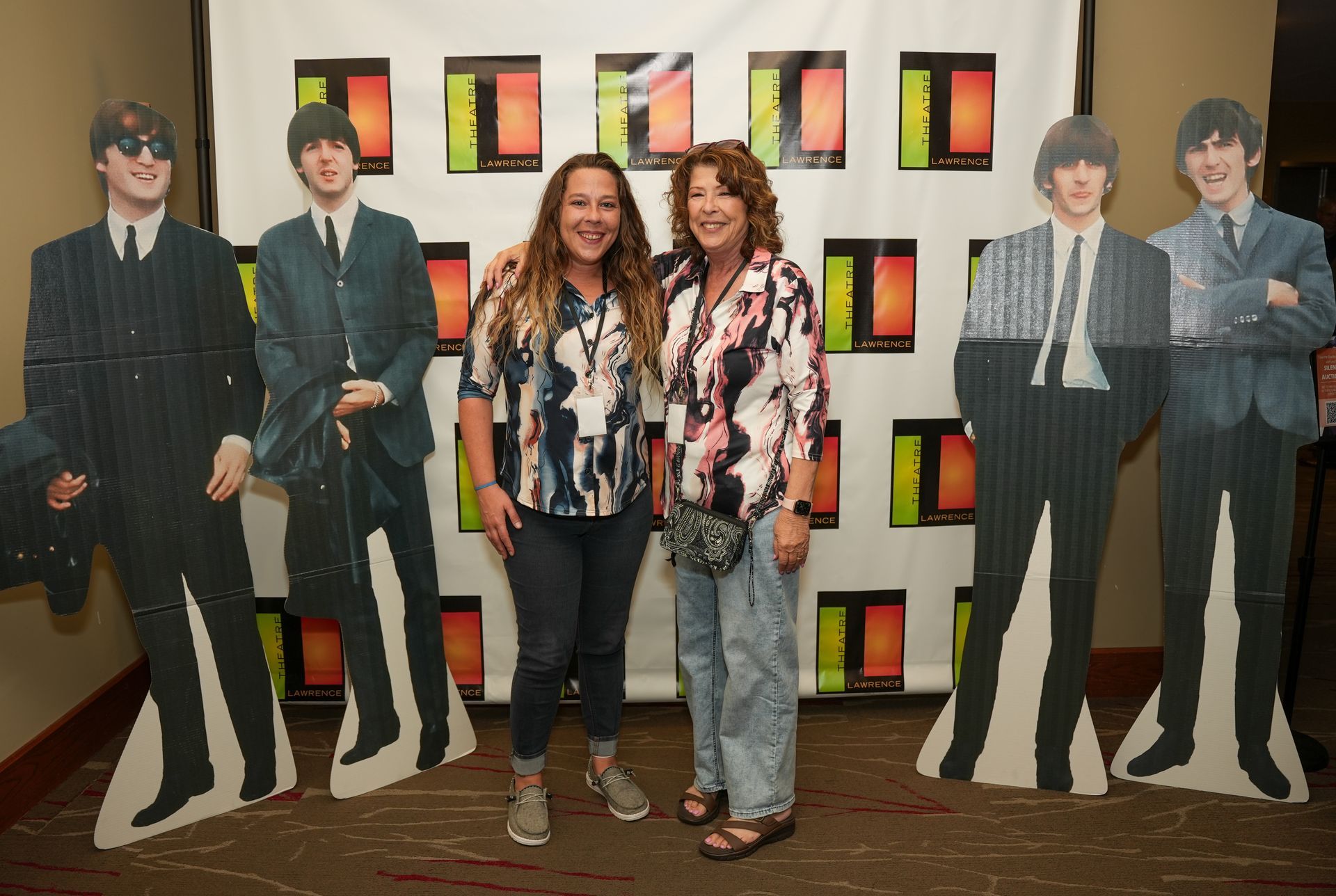Two women pose with cardboard cutouts of The Beatles.