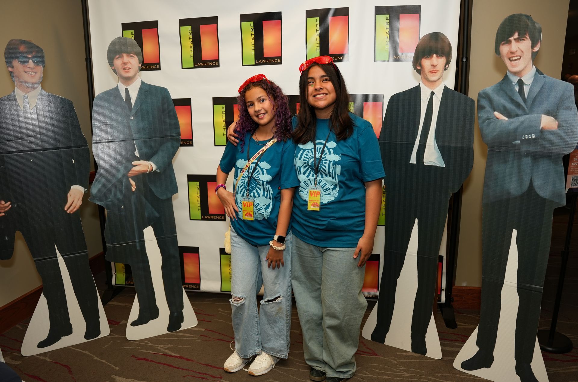 Two people posing with Beatles standees at an event.