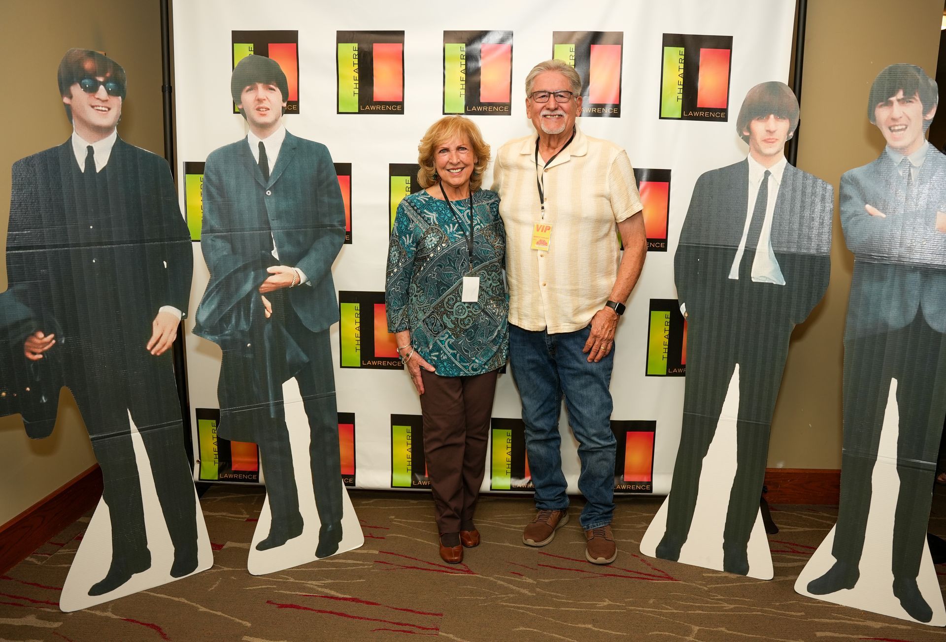 Couple poses with Beatles cardboard cutouts at an event.