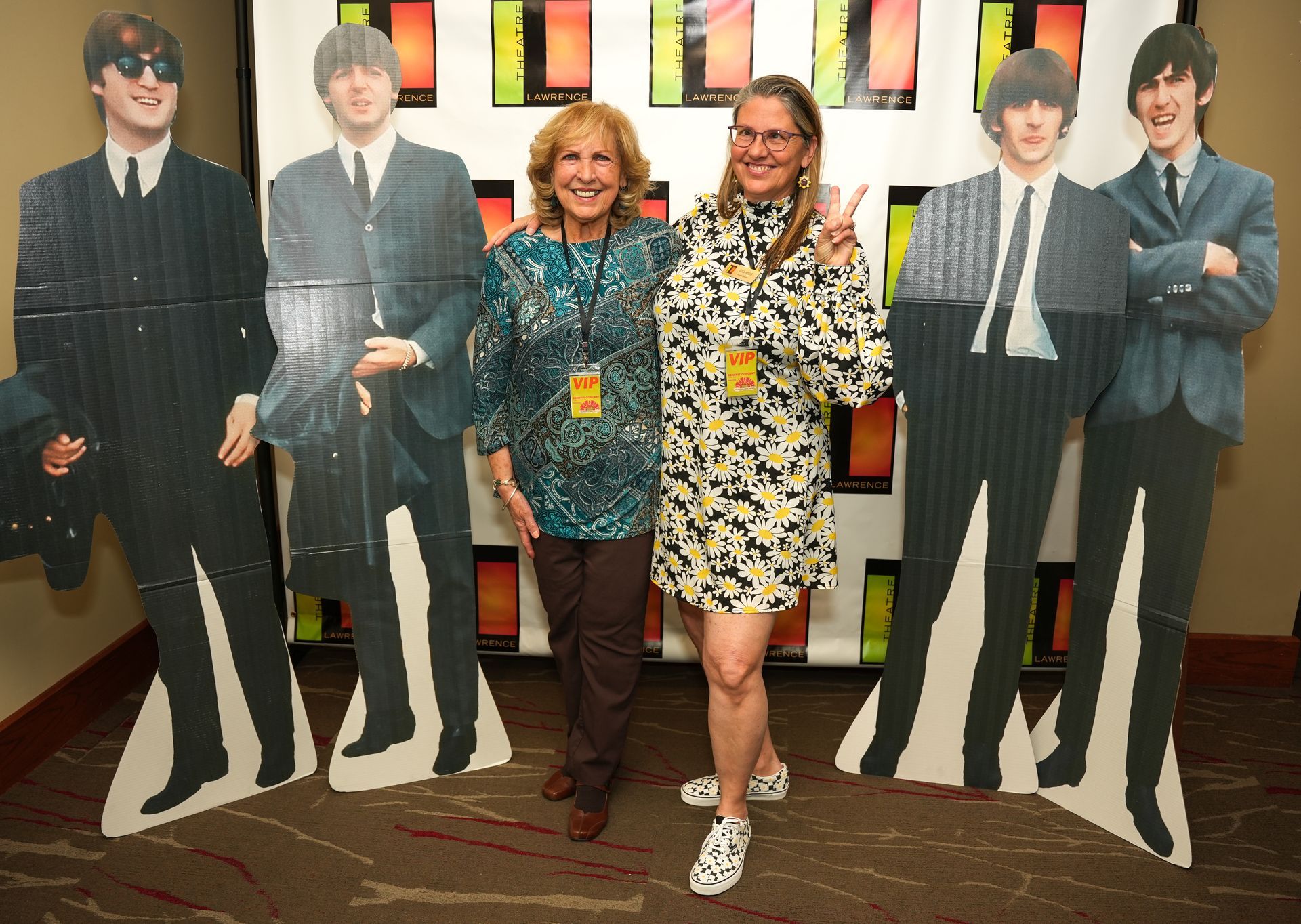 Two women pose with Beatles cardboard cutouts at an event.