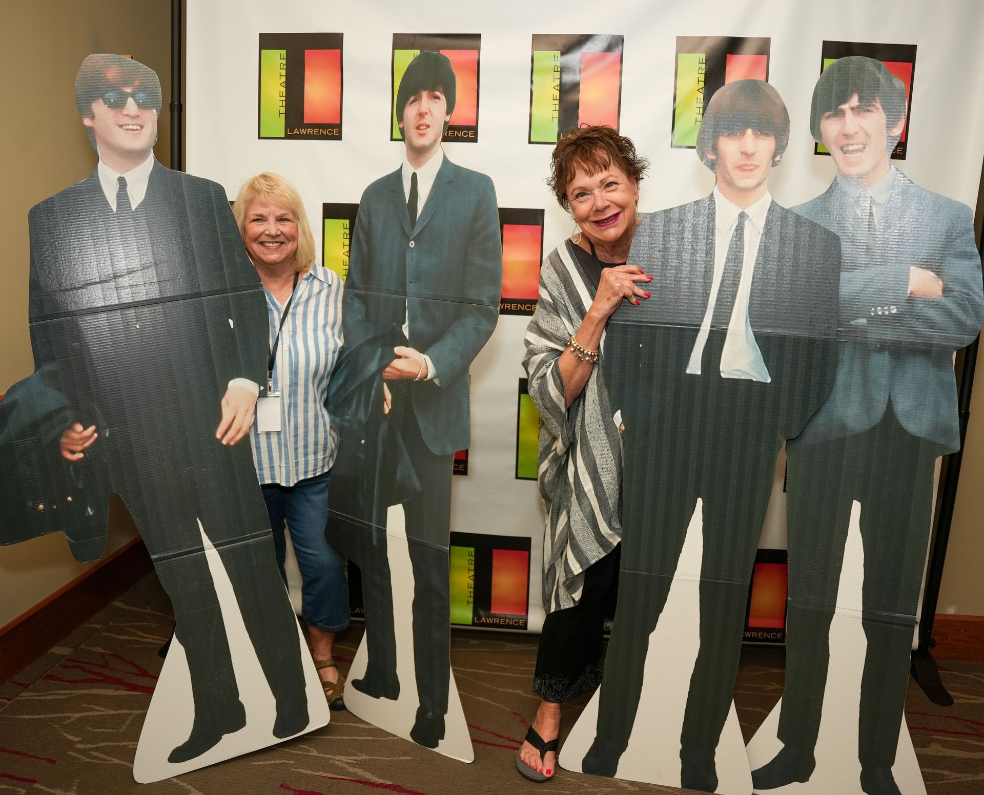 Two women pose with cardboard cutouts of The Beatles.