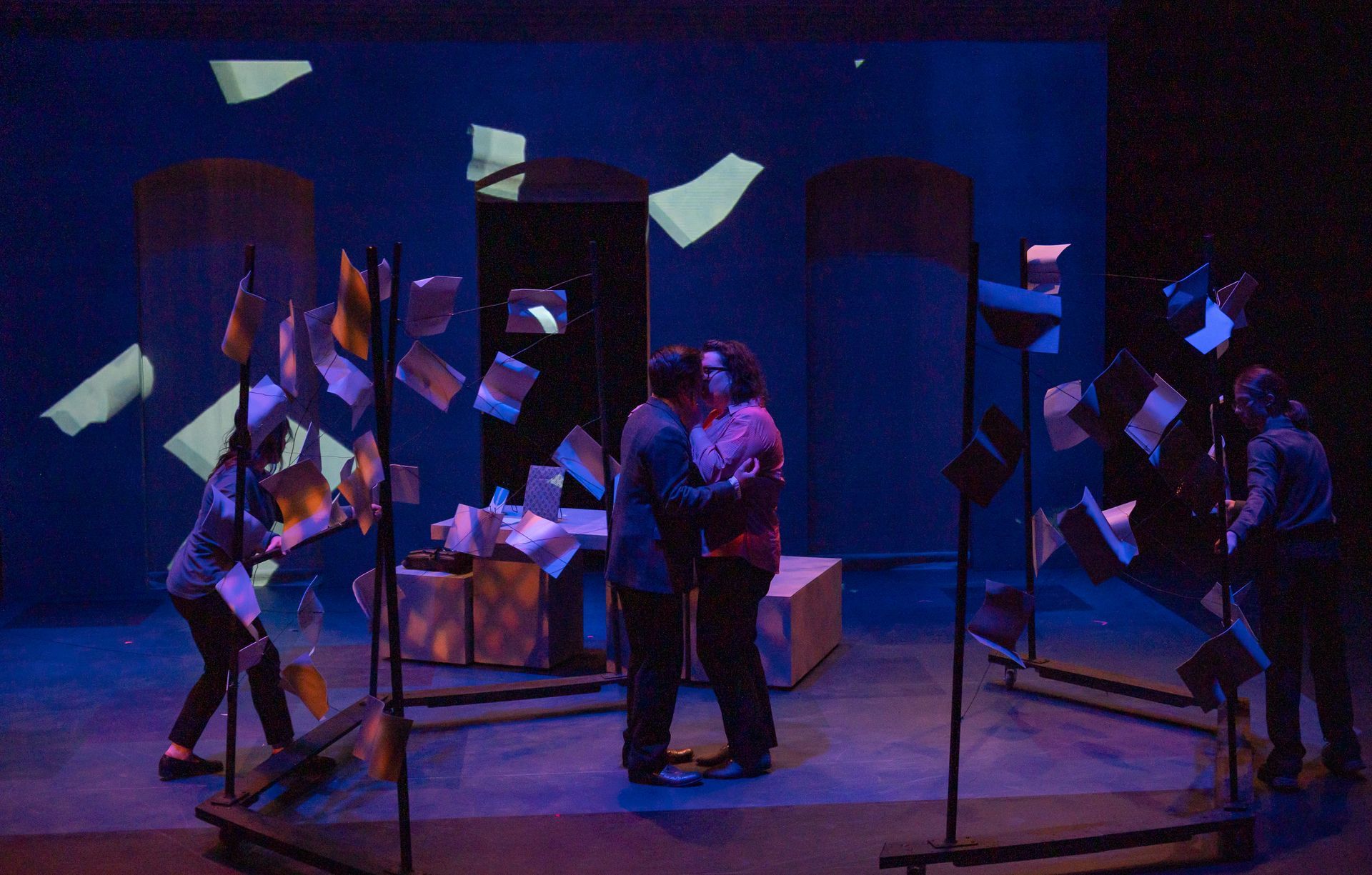 A group of people are standing on a stage in front of a blue light.