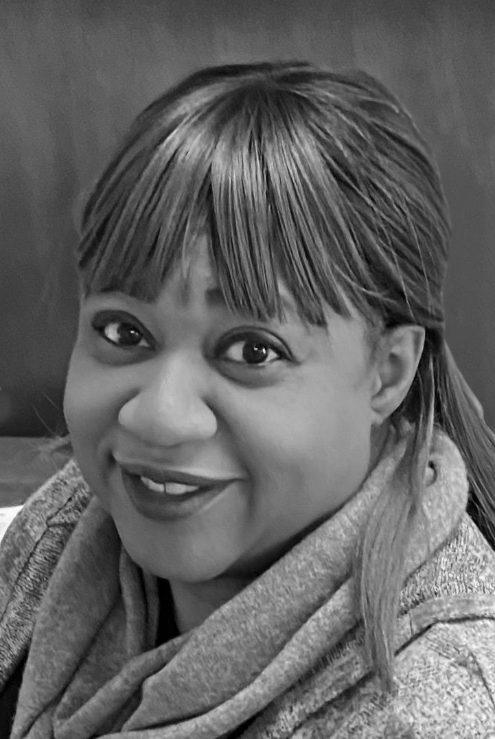 Black and white portrait of a smiling woman with bangs and a scarf.