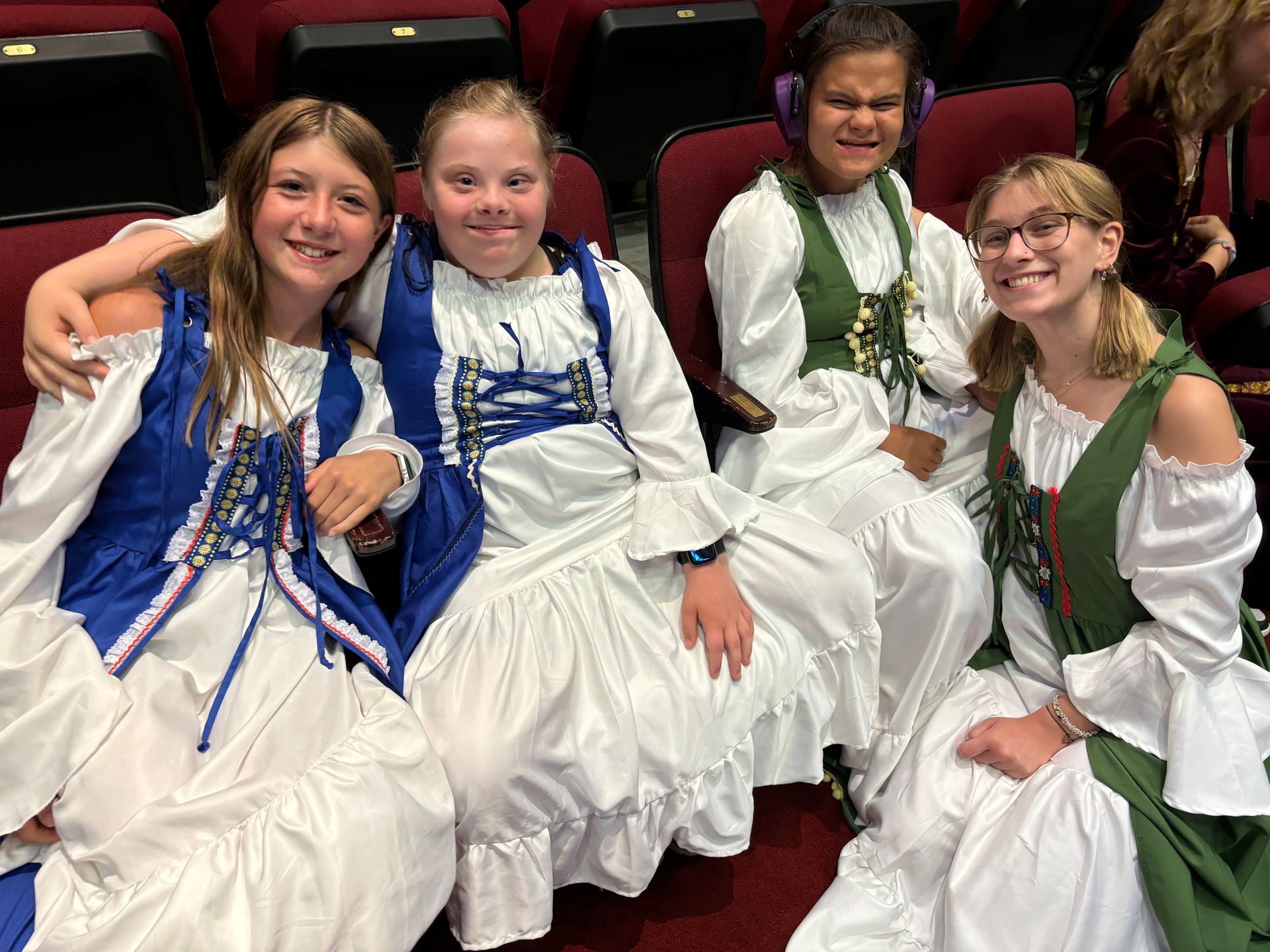 A group of young girls dressed in costumes are sitting in a theater.