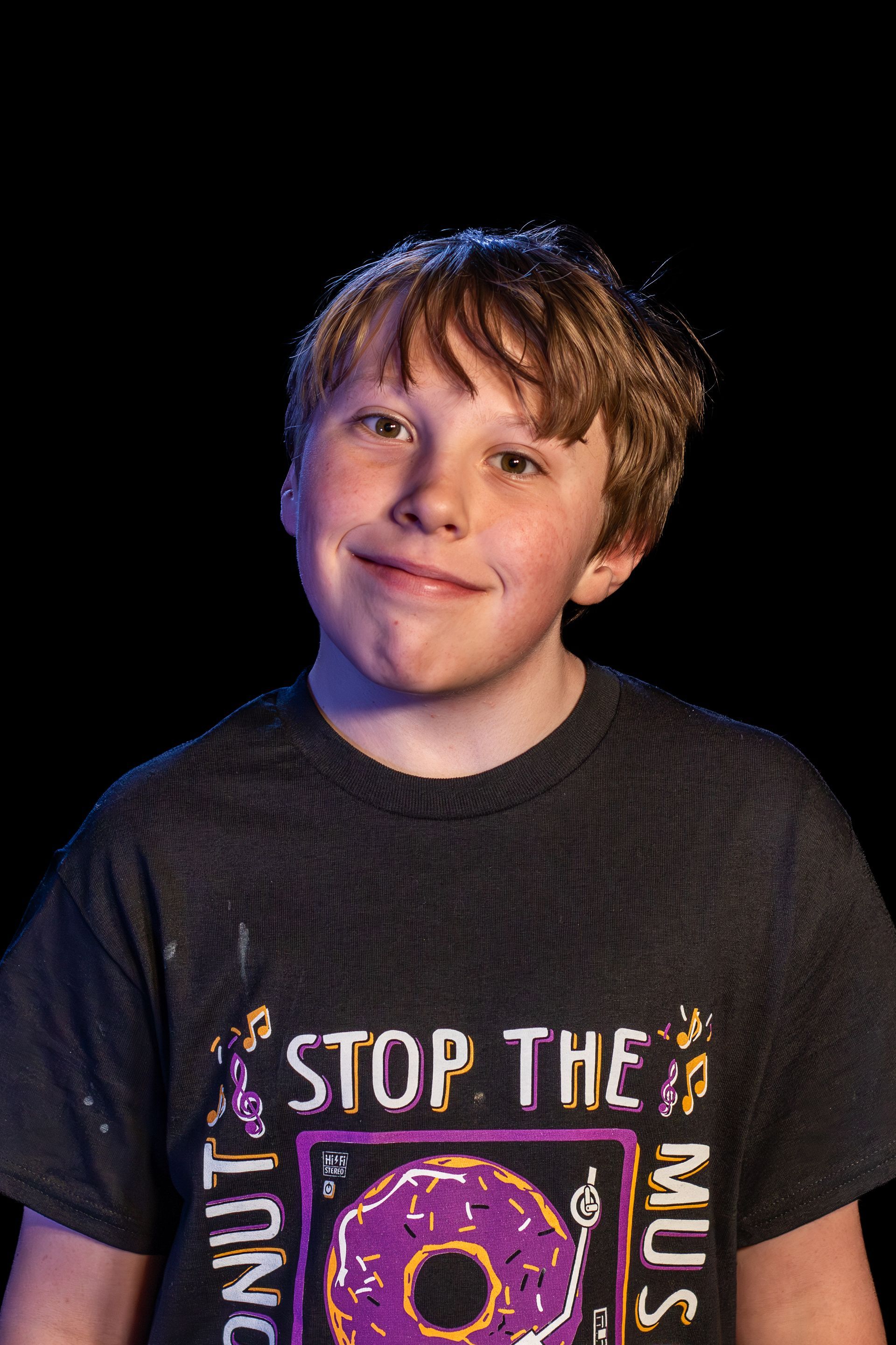Boy with brown hair, wearing a gray t-shirt that says 