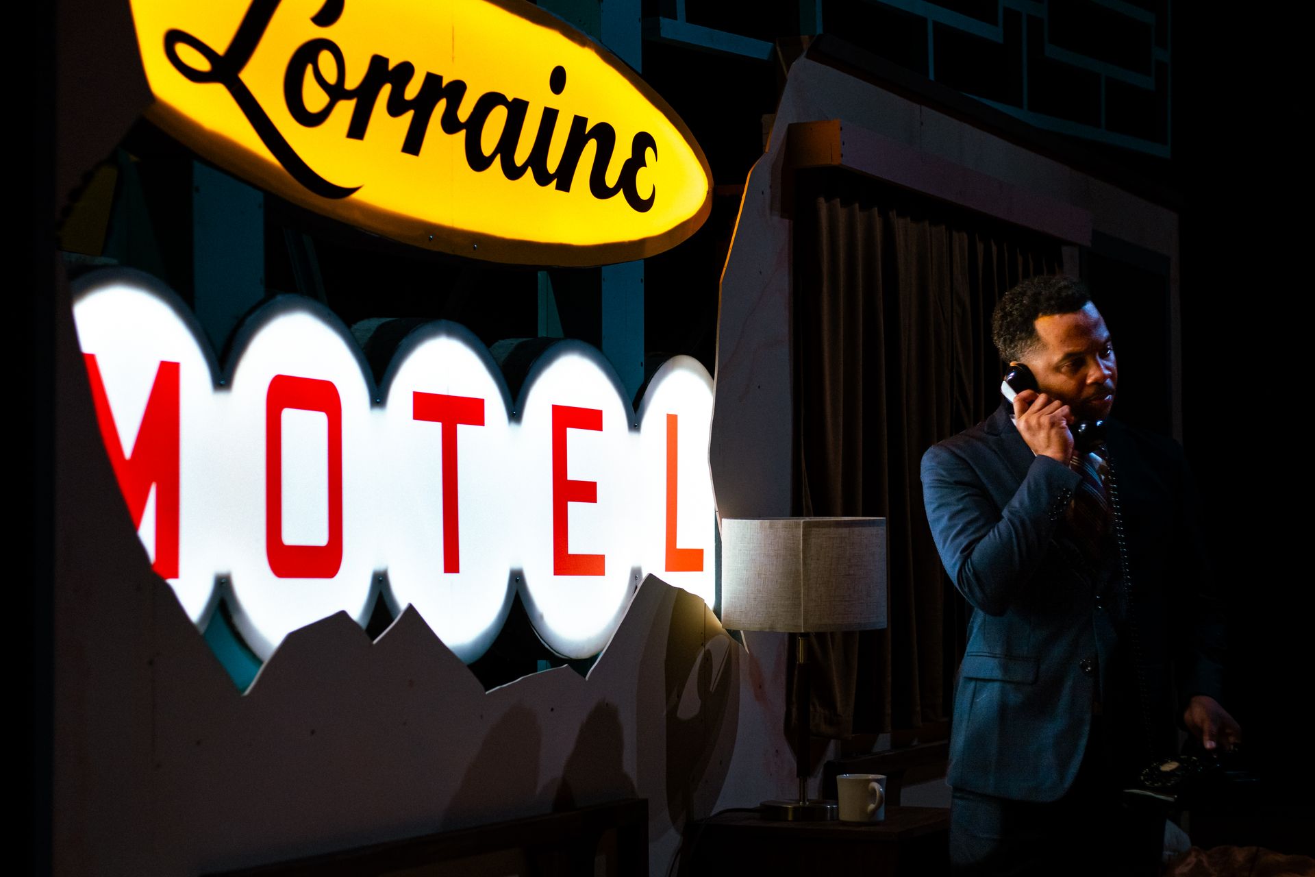 Man on phone near a Lorraine Motel sign. Sign is lit with the word