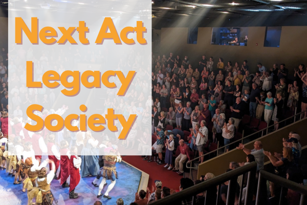 A theater audience applauds a stage performance, with