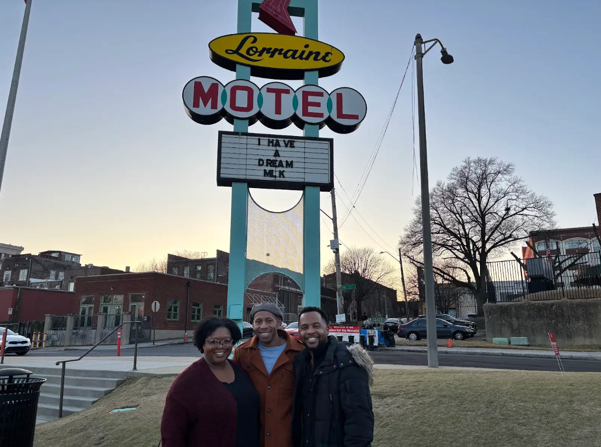 Three people posing in front of the Lorraine Motel sign in Memphis.