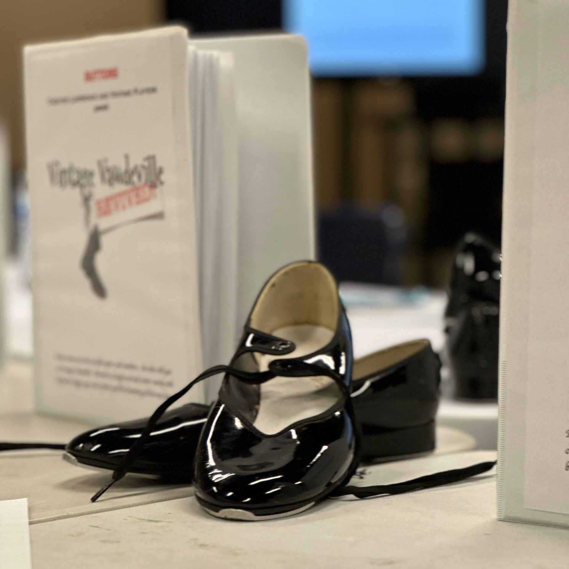 Black tap shoes in front of a book titled 