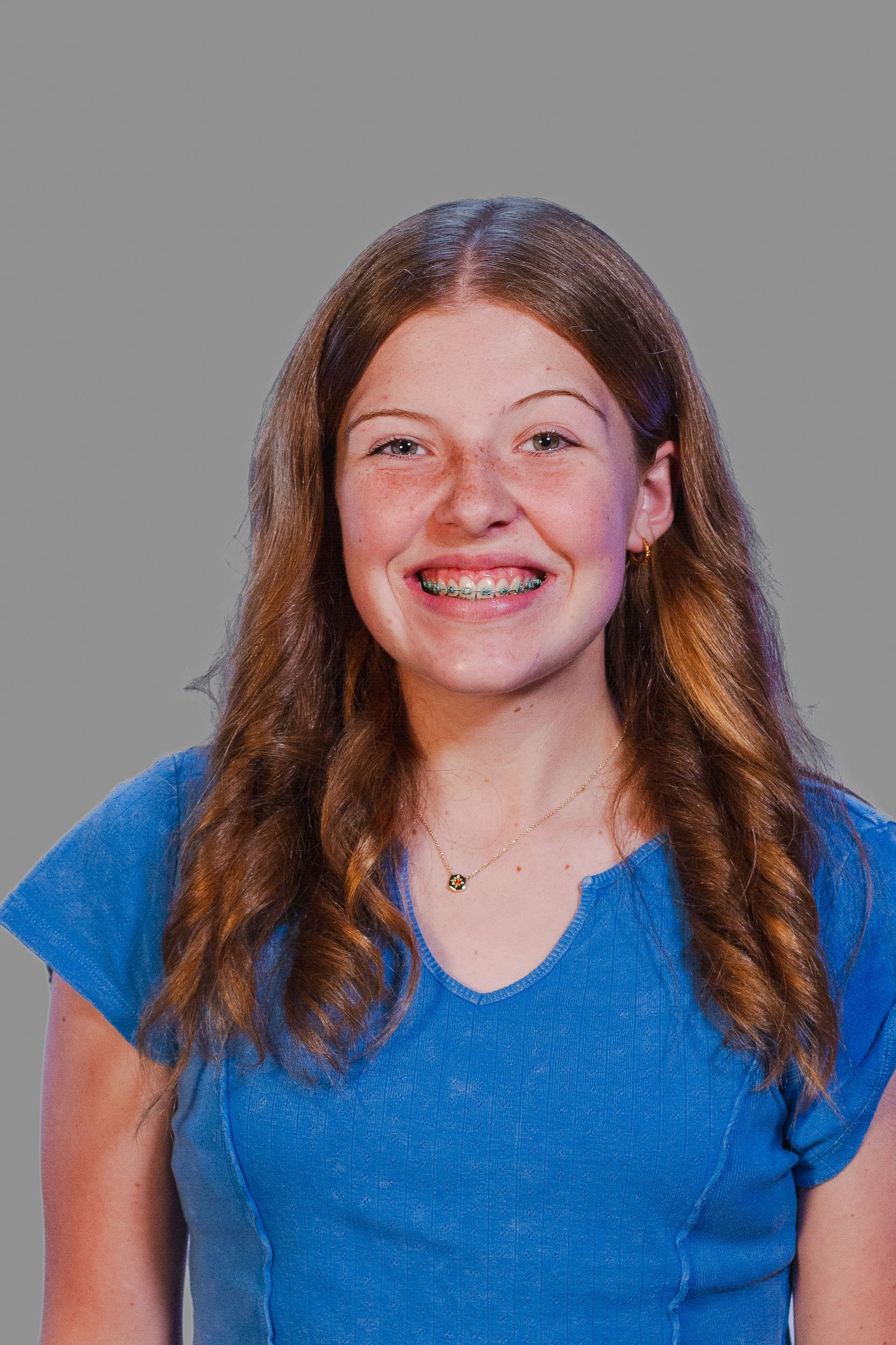 Smiling person with braces in a blue top against a gray background.