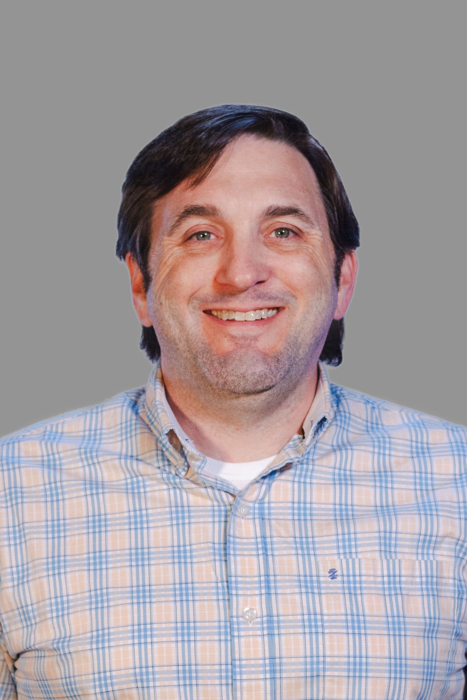 Man smiling in plaid shirt.