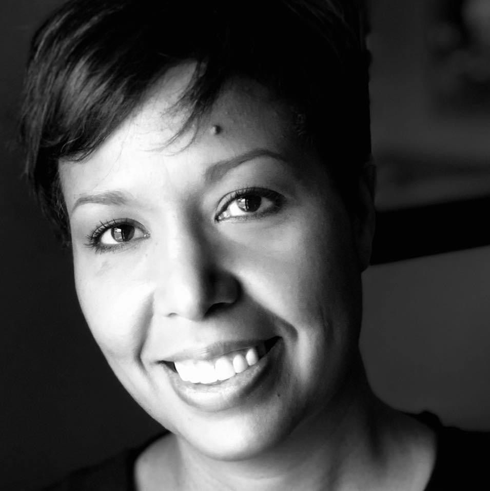 Woman with short dark hair smiles at the camera in a black and white close-up portrait.