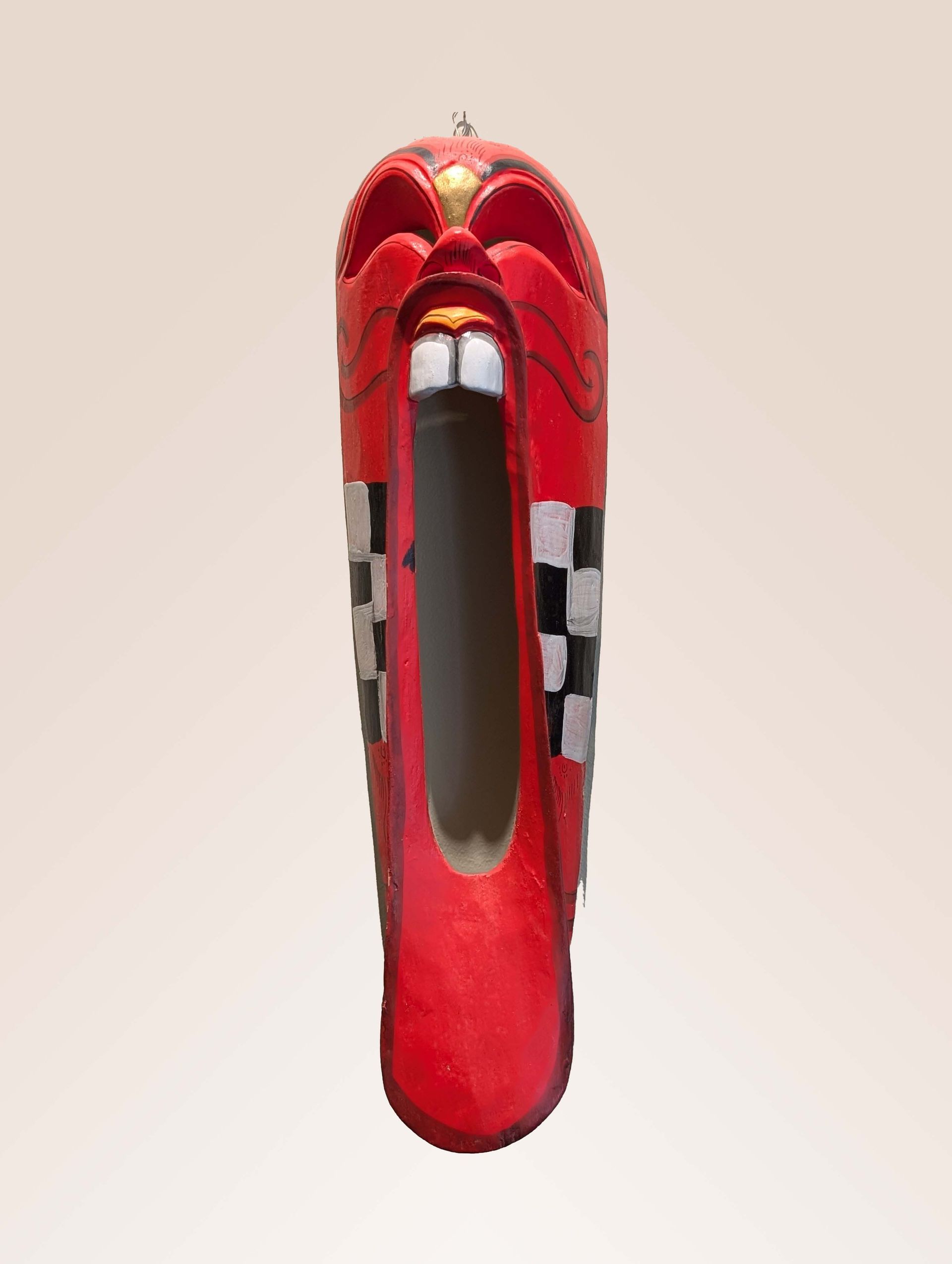 Red wooden mask with open mouth, white teeth, and checkered pattern.