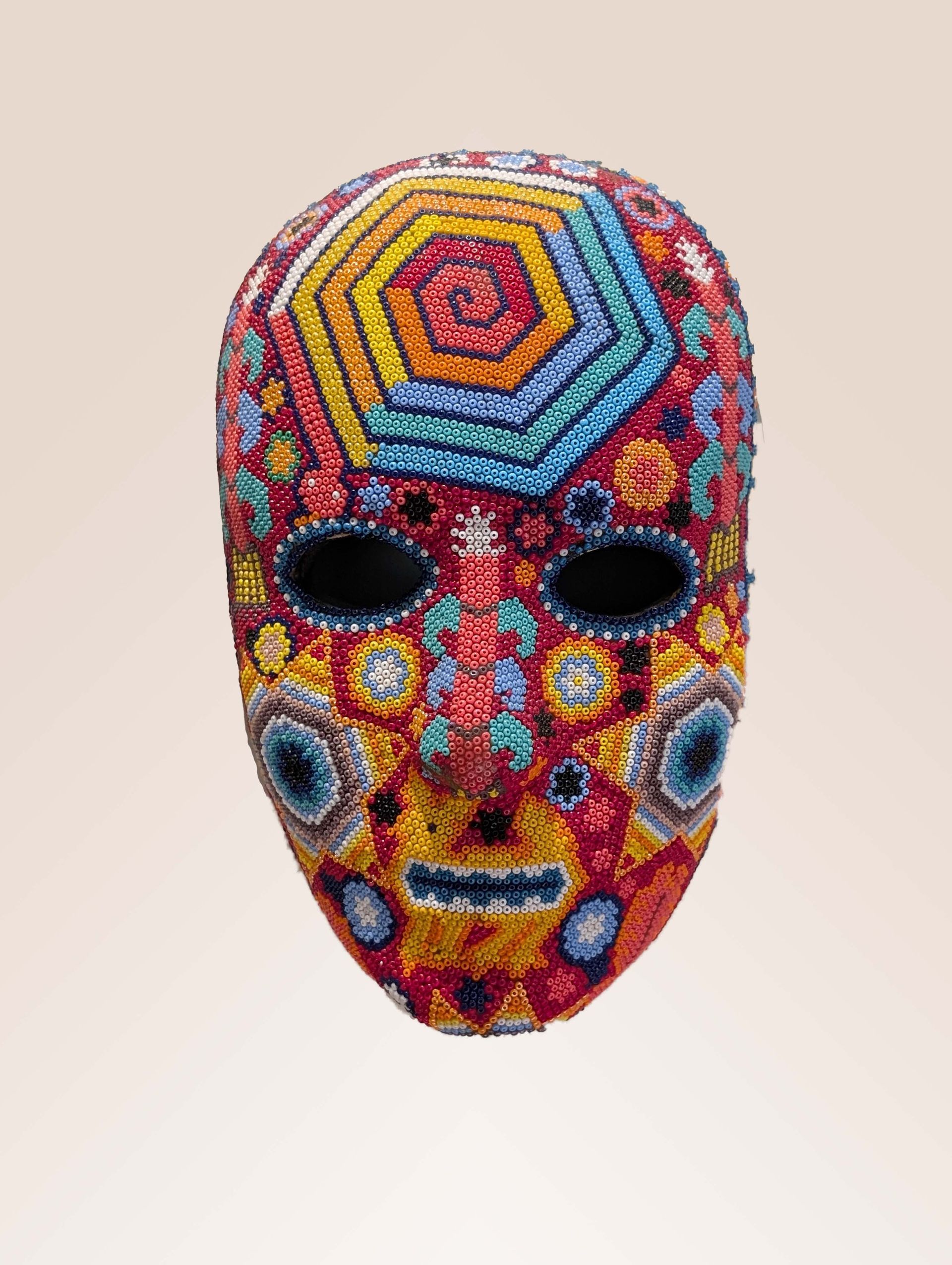 Colorful embroidered mask with geometric and floral patterns.