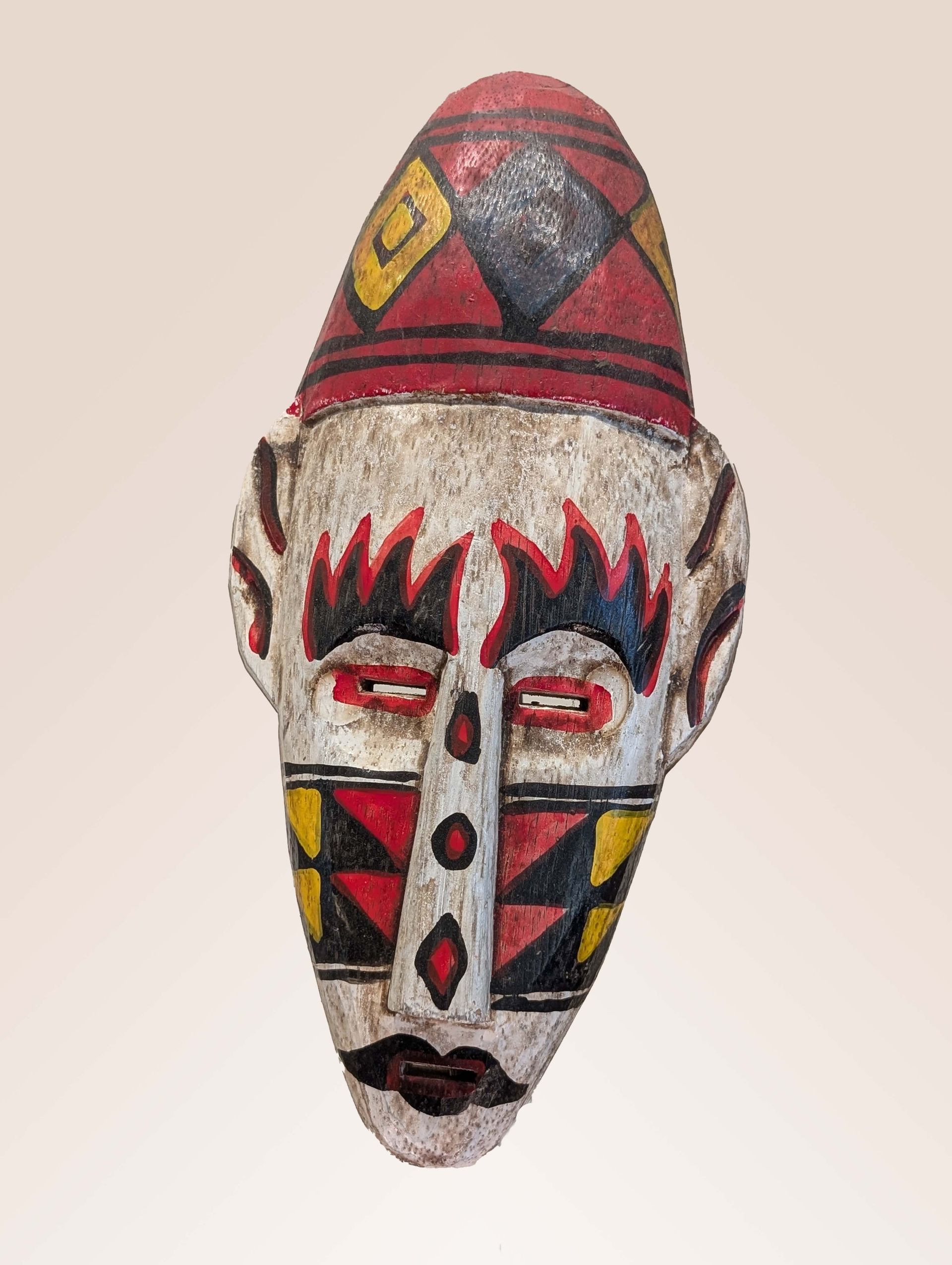 Wooden mask with red, yellow, and black geometric designs on white; bulbous head.