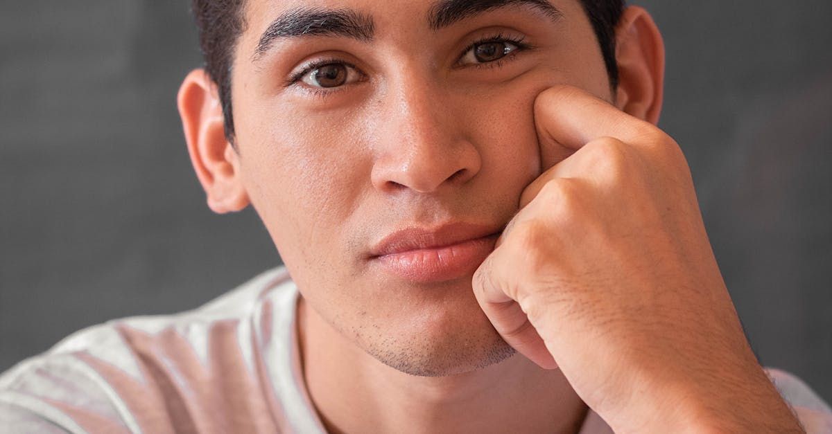 Young man with brown eyes, resting his chin on his hand, looking at the camera.