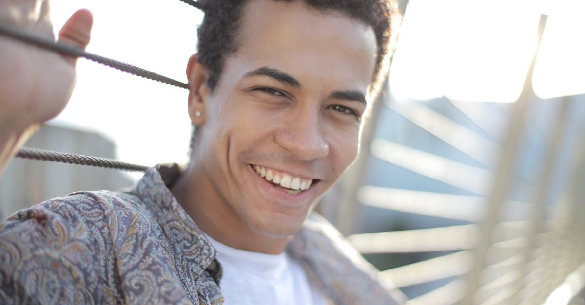 Smiling young man with curly hair; outdoor setting, holding a cable.