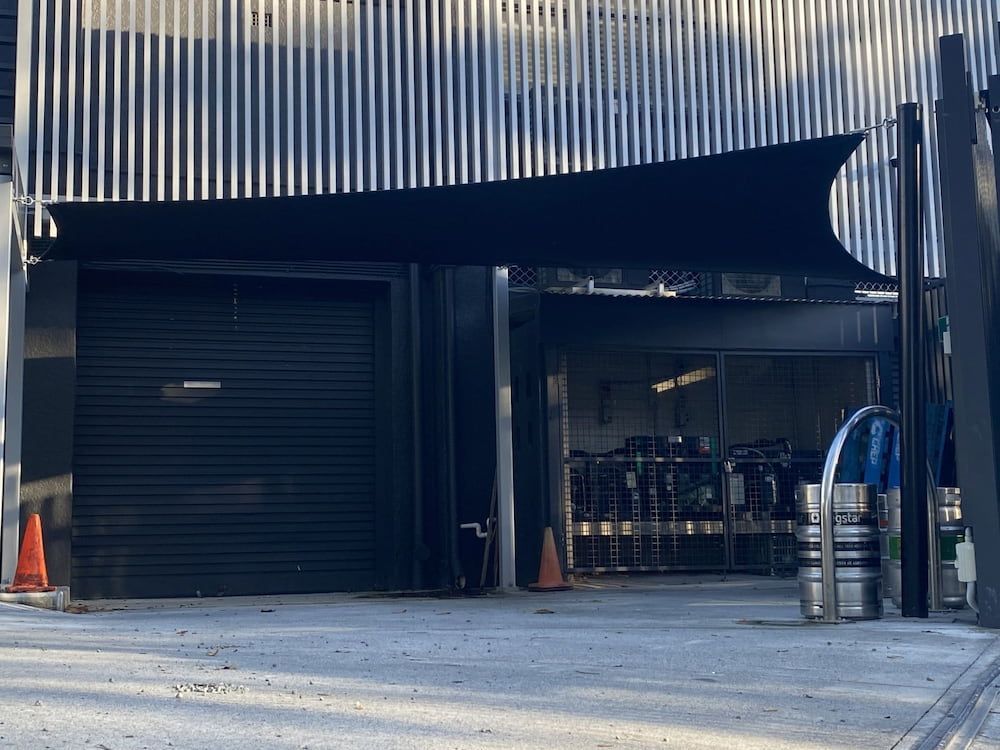 A Large Building With A Black Garage Door And A Black Awning Over It — SPF Shades and Sails in Tweed Heads West, NSW