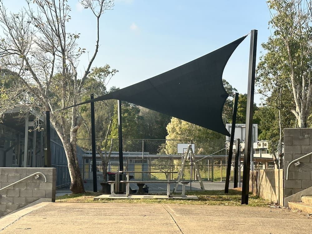 A Large Black Umbrella Is Sitting On Top Of A Concrete Surface In A Park β SPF Shades and Sails in Tweed Heads West, NSW