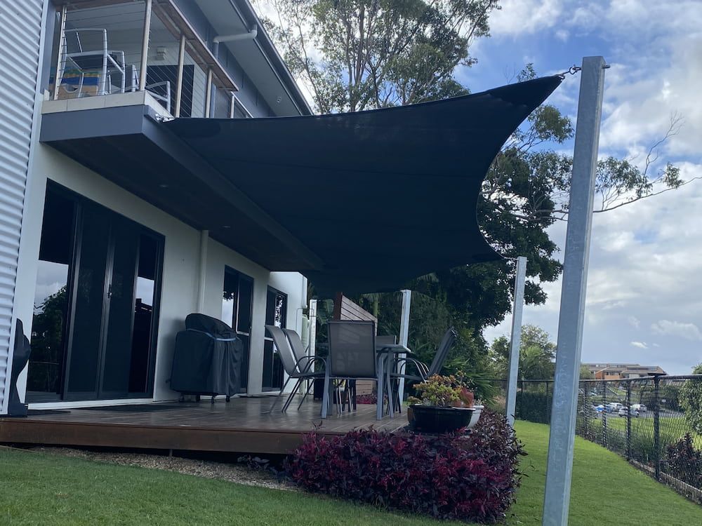 A Large House With A Large Black Umbrella Over The Deck — SPF Shades and Sails in Lismore, NSW