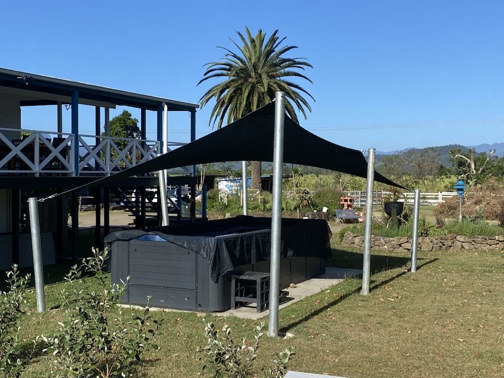 A Black Umbrella Is Covering A Hot Tub In Front Of A House β SPF Shades and Sails in Tweed Heads, NSW