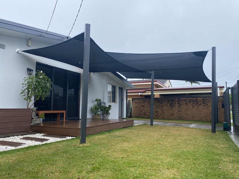 A Black Shade Sail Is Covering The Backyard Of A House — SPF Shades and Sails in Tweed Heads West, NSW