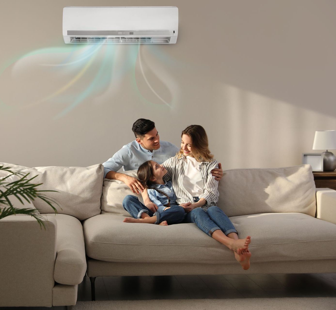A family is sitting on a couch under an air conditioner.
