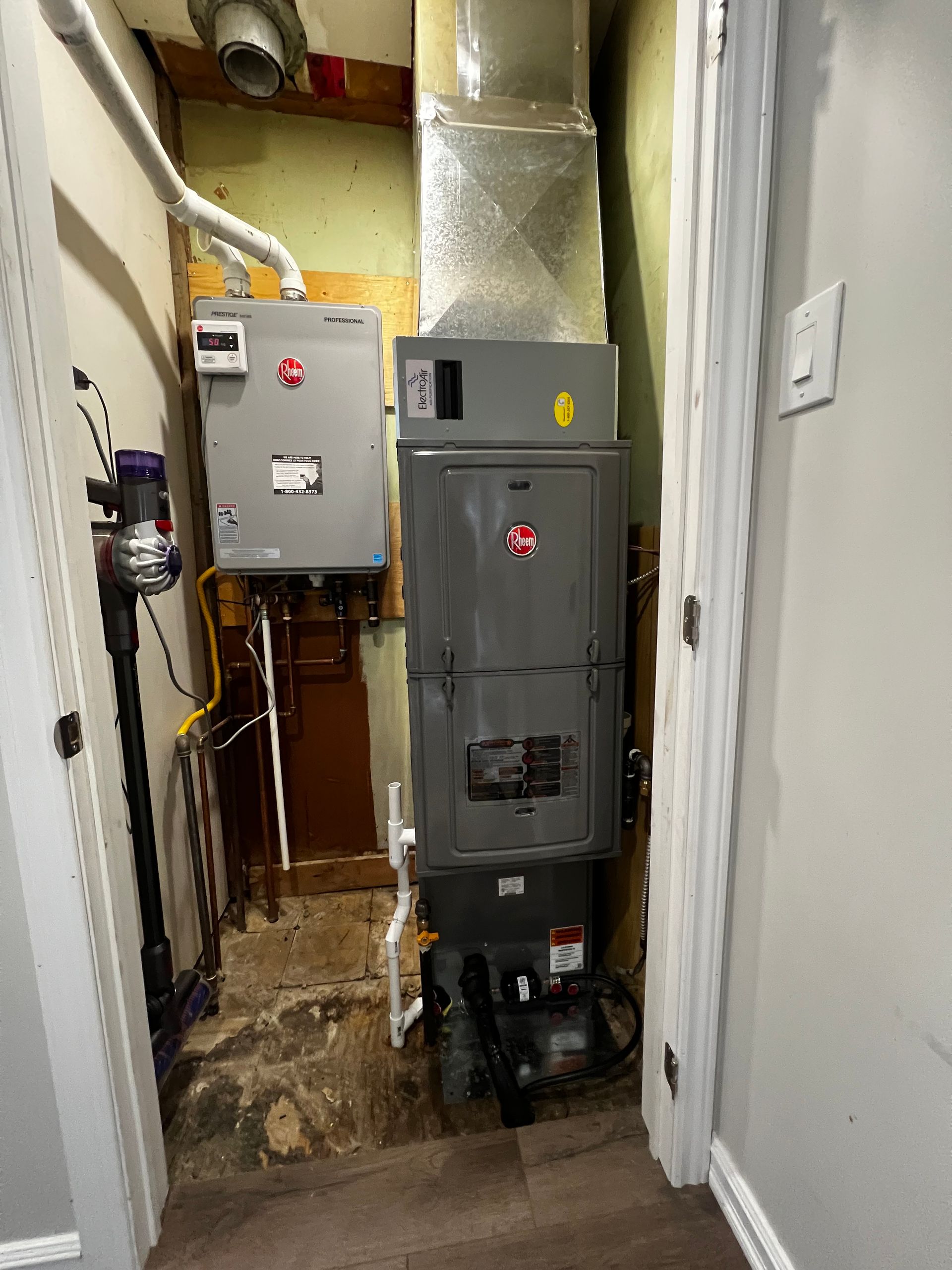 A boiler is sitting in a hallway next to a door.