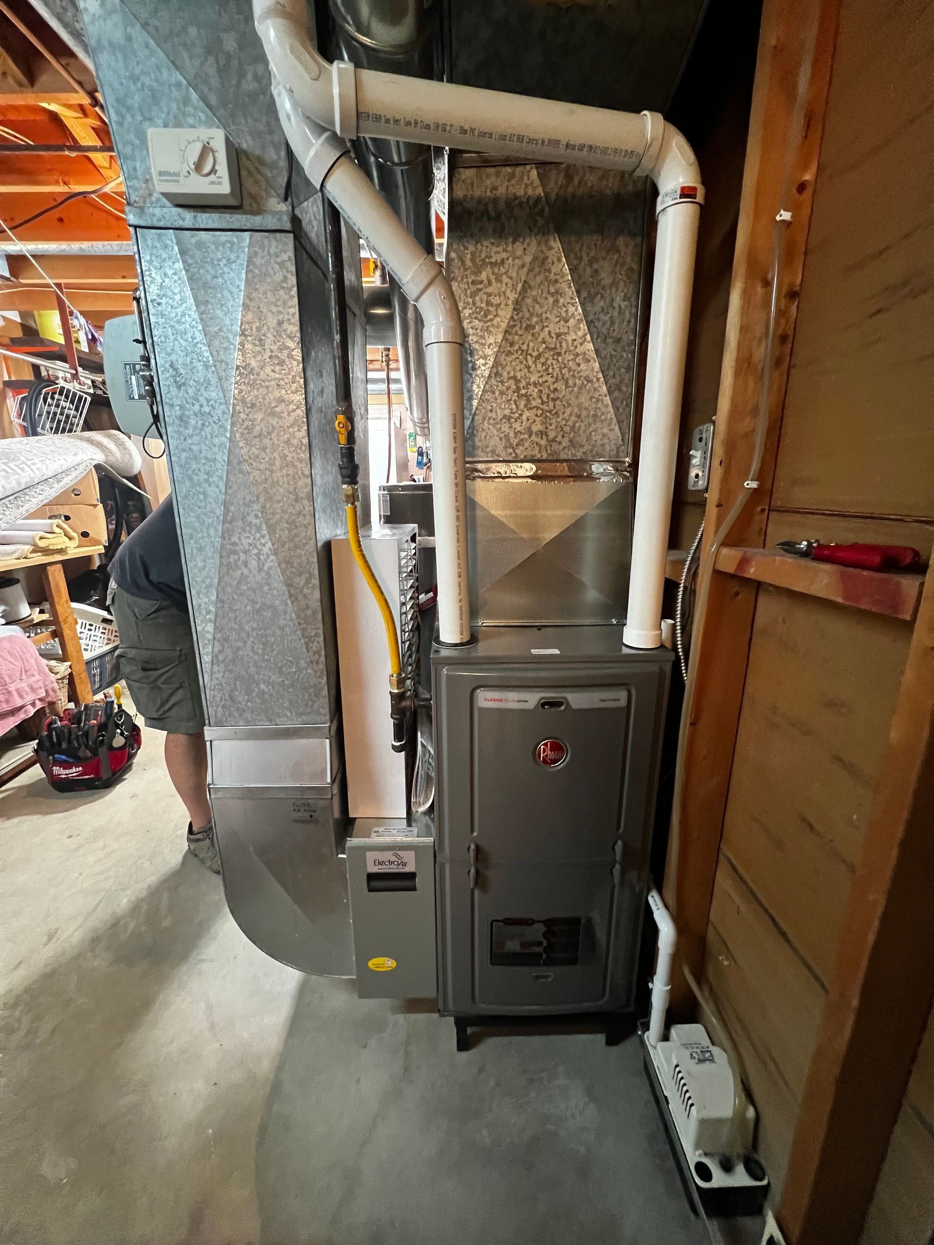 A man is working on a heating system in a basement.