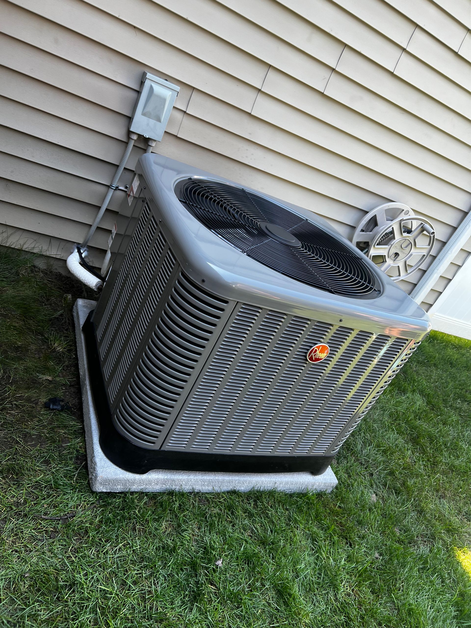 A large air conditioner is sitting on the side of a house.