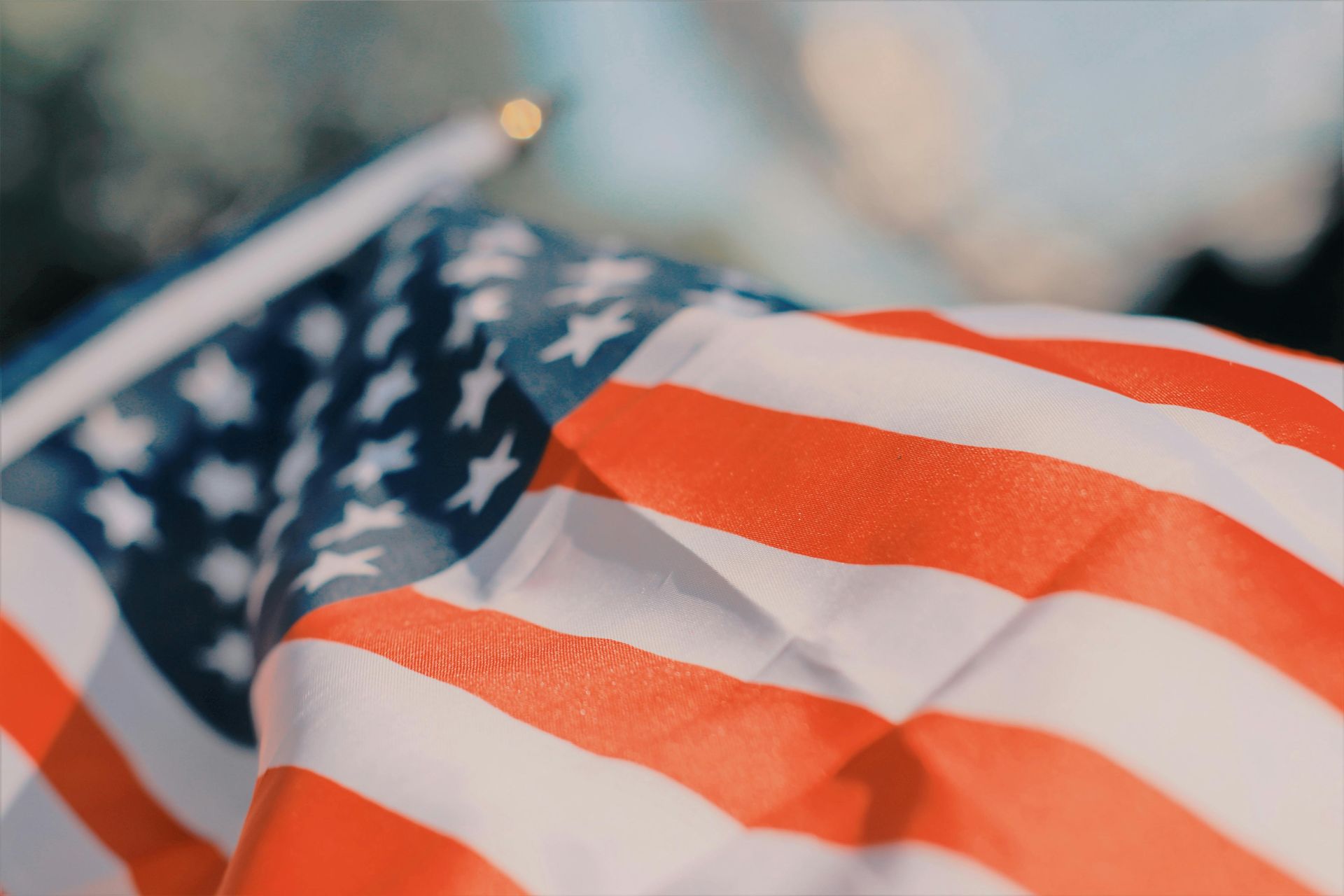 A close-up view of an American flag waving in the wind against a soft, blurred background.